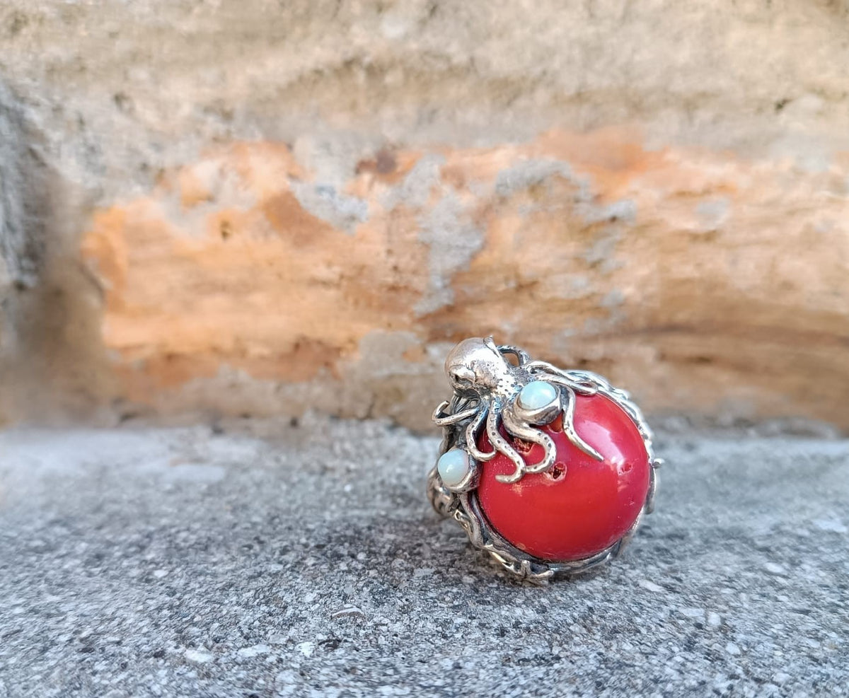anello scultura oceanica con tentacoli di polpo in argento, sfera di corallo rosso e due opali bianchi