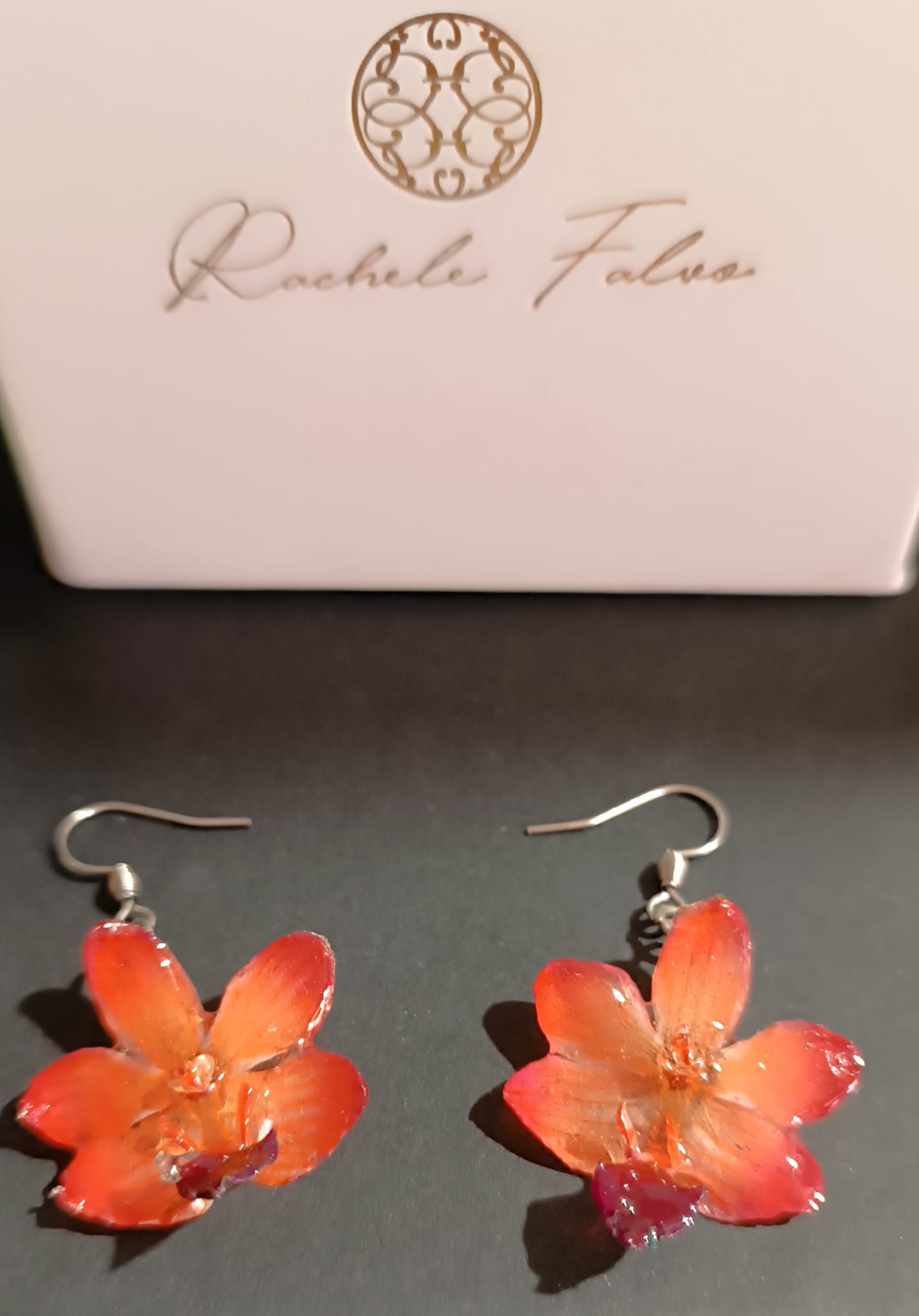 orecchini pendenti artigianali con piccole orchidee vere in resina trasparente colore  arancione, con ganci in argento.