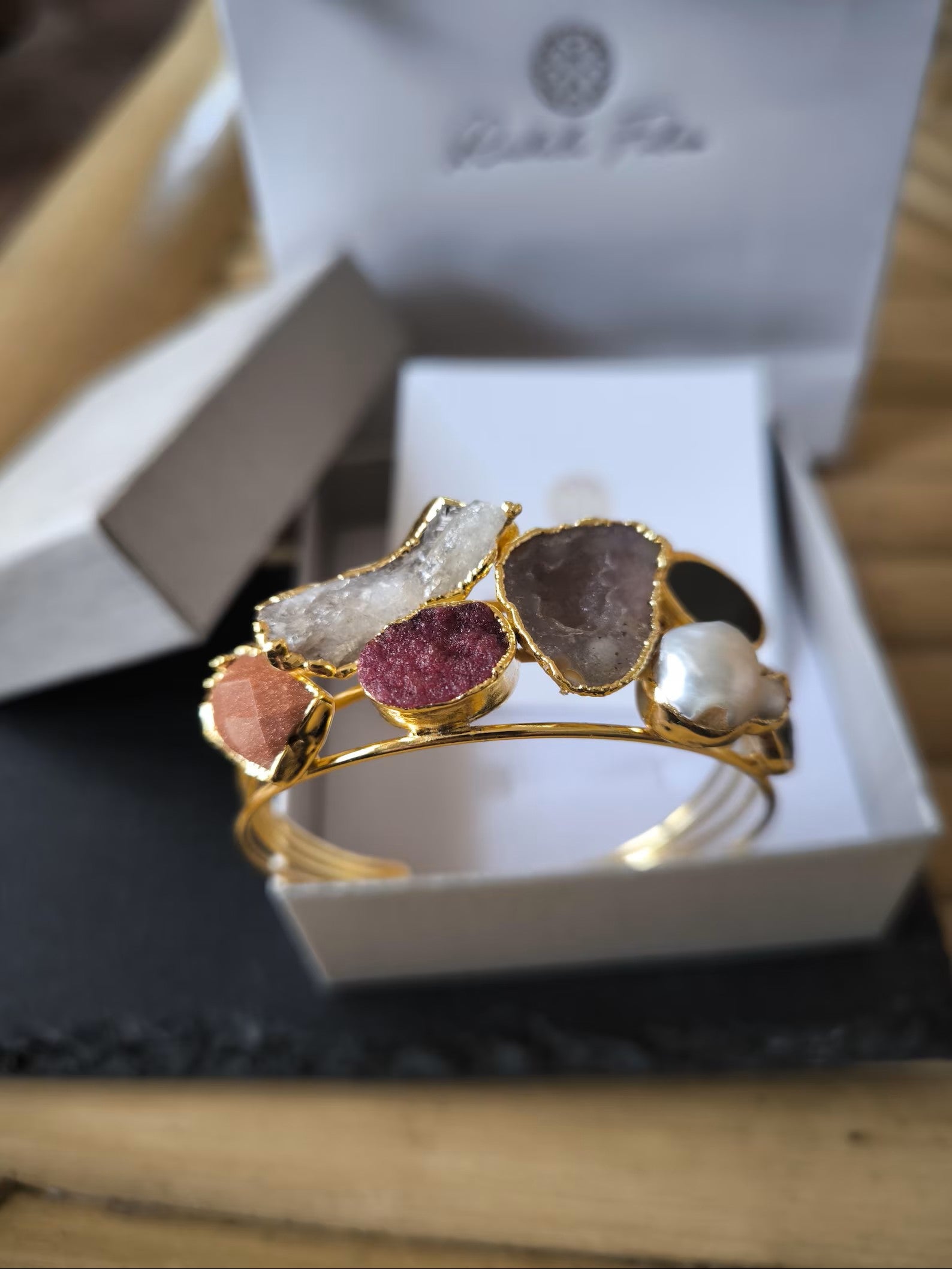 bracciale cuff dorato multifilo di Rachele Falvo con incastonati una perla barocca, un rubino grezzo, agate naturali e un'avventurina sfaccettata