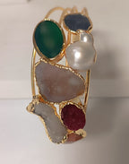 bracciale cuff dorato multifilo di Rachele Falvo con incastonati una perla barocca, un rubino grezzo, agate naturali e un'avventurina sfaccettata