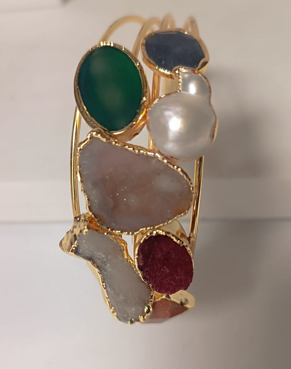 bracciale cuff dorato multifilo di Rachele Falvo con incastonati una perla barocca, un rubino grezzo, agate naturali e un'avventurina sfaccettata