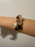 bracciale cuff dorato multifilo di Rachele Falvo con incastonati una perla barocca, un rubino grezzo, agate naturali e un'avventurina sfaccettata
