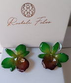 orecchini a perno artigianali realizzati con intere orchidee vere dai petali verde brillante e centro viola bordeaux, protette da resina lucida