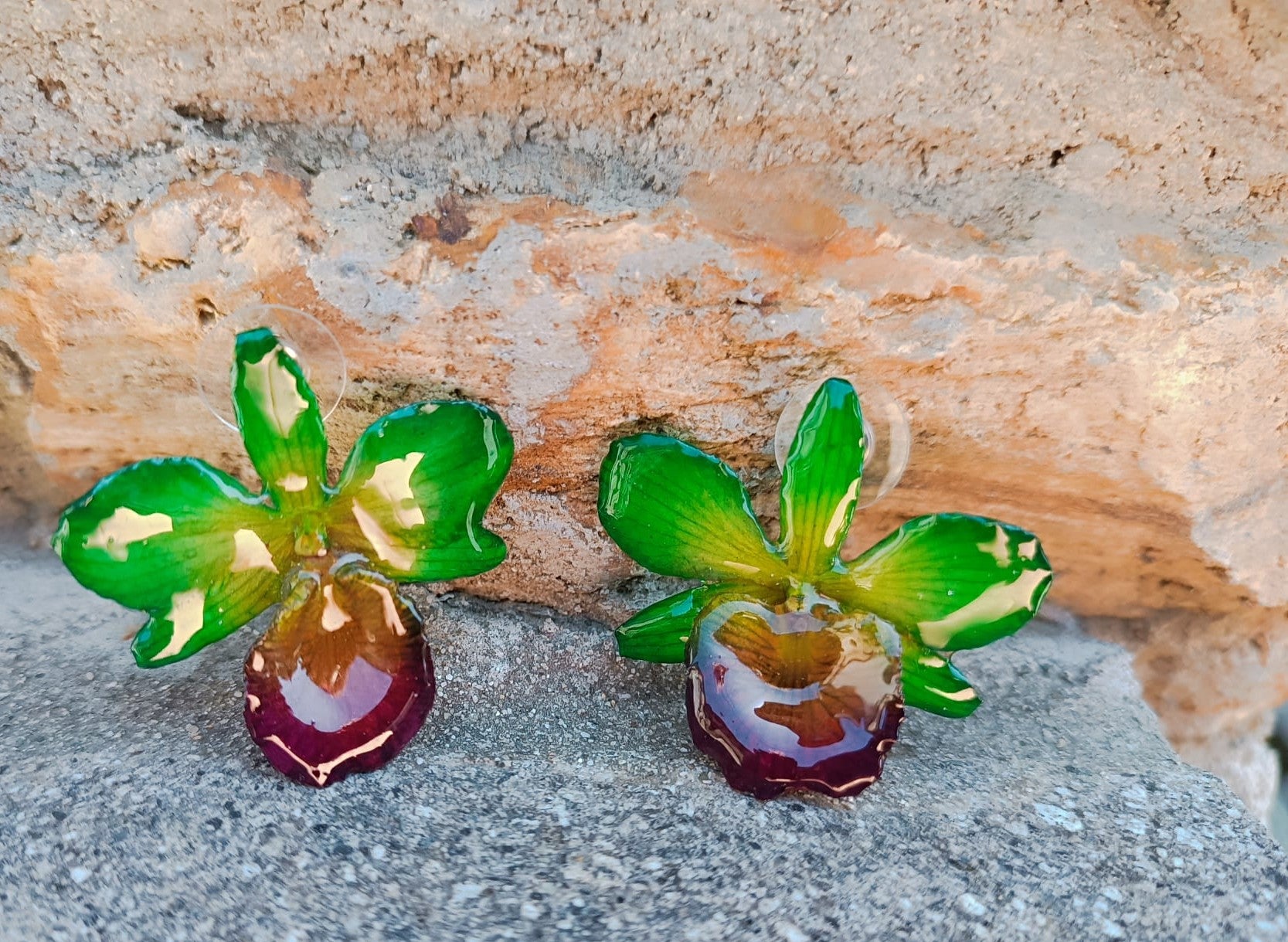 orecchini a perno artigianali realizzati con intere orchidee vere dai petali verde brillante e centro viola bordeaux, protette da resina lucida