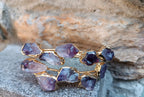 bracciale rigido aperto a fascia di Rachele Falvo in bronzo placcato oro con cristalli grezzi di ametista viola naturale