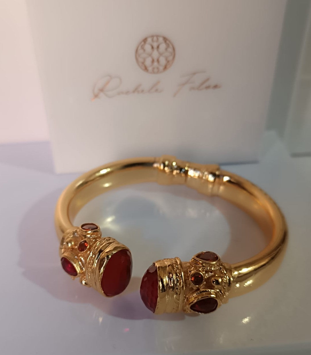 bracciale rigido in bronzo dorato a molla di Rachele Falvo in stile etrusco bizantino con intarsi e grandi diaspri rossi naturali e topazi mora