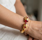 bracciale rigido in bronzo dorato a molla di Rachele Falvo in stile etrusco bizantino con intarsi e grandi diaspri rossi naturali e topazi mora