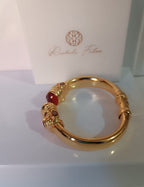 bracciale rigido in bronzo dorato a molla di Rachele Falvo in stile etrusco bizantino con intarsi e grandi diaspri rossi naturali e topazi mora