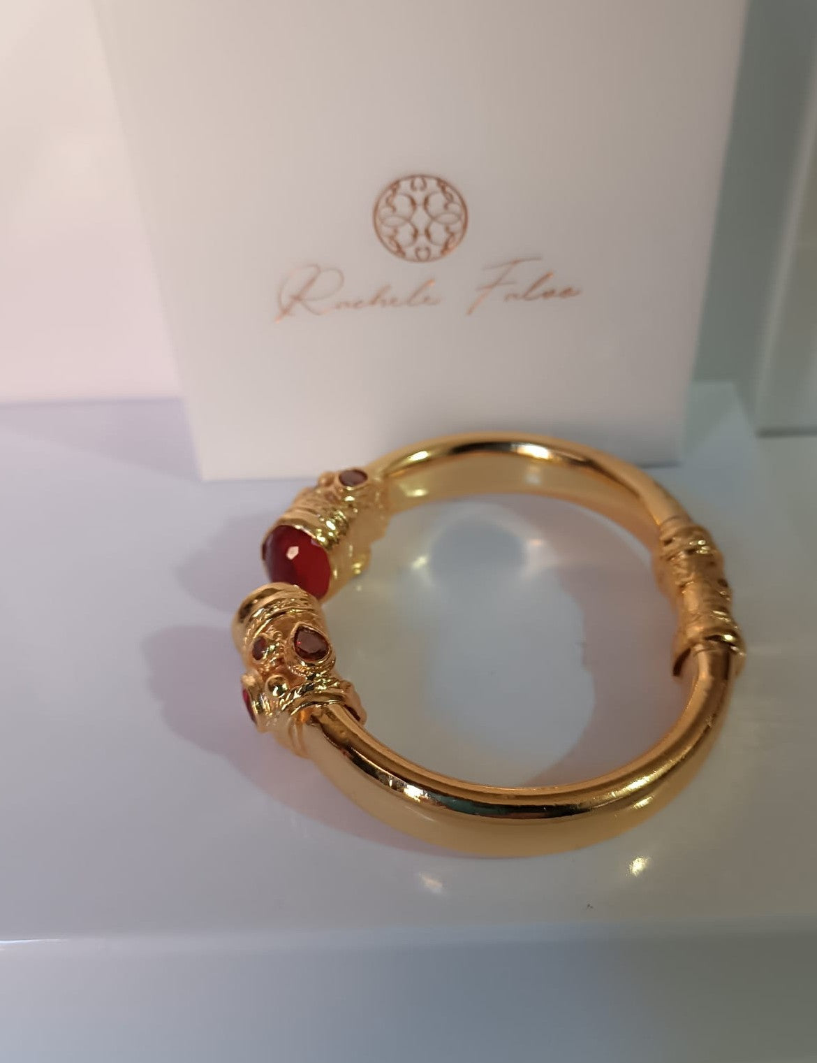 bracciale rigido in bronzo dorato a molla di Rachele Falvo in stile etrusco bizantino con intarsi e grandi diaspri rossi naturali e topazi mora
