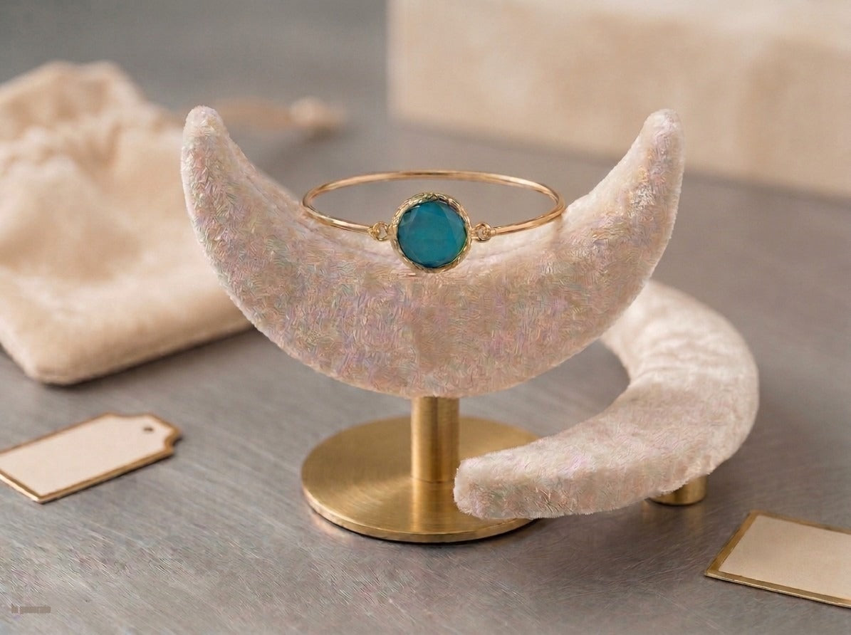 bracciale rigido in bronzo placcato oro opaco di Rachele Falvo con pietra centrale di occhio di gatto azzurro naturale sfaccettato.