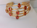 bracciale a cinque fili in bronzo dorato martellato di Rachele Falvo con incastonati nove granati rossi naturali sfaccettati da 3 carat