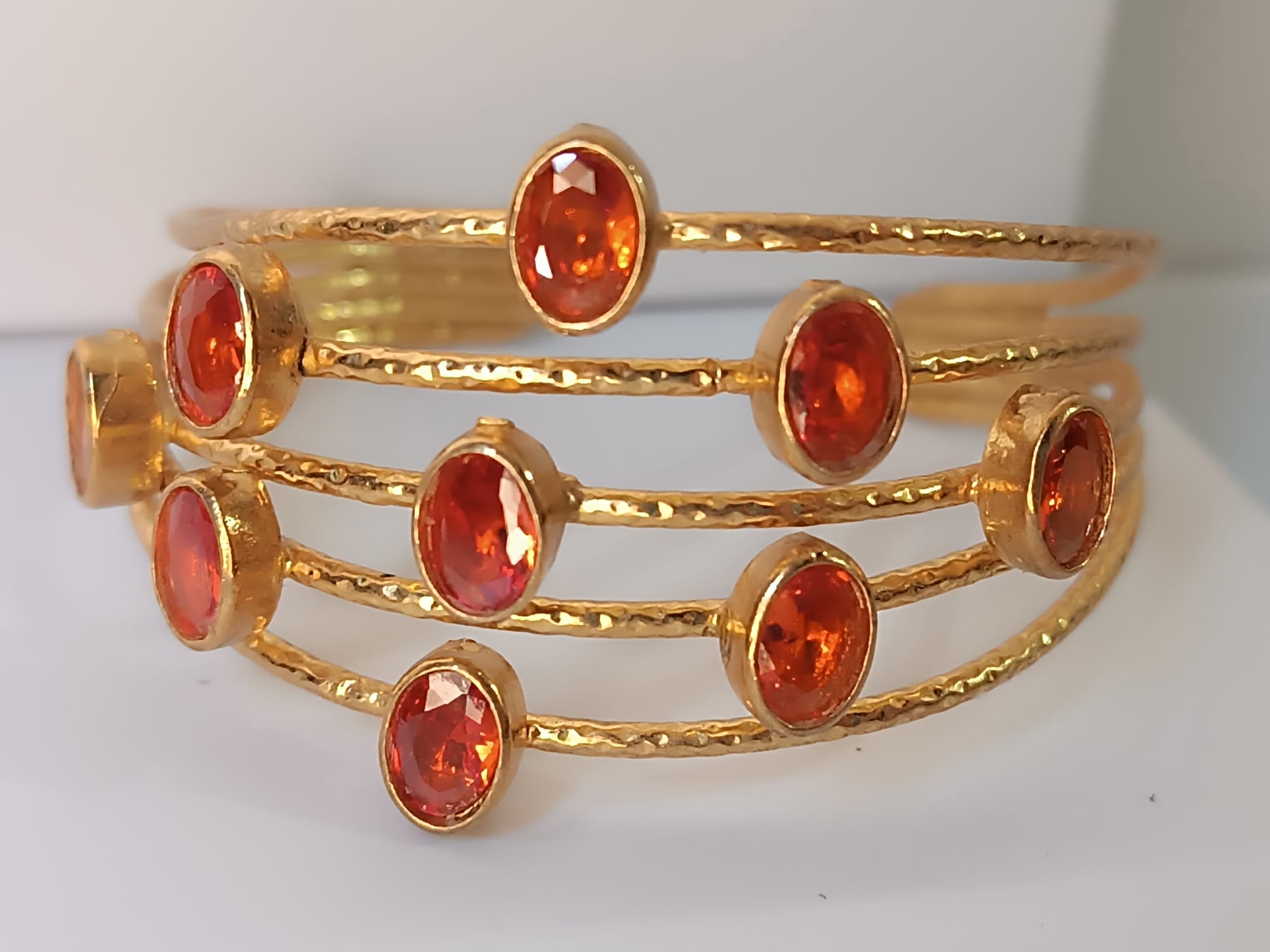 bracciale a cinque fili in bronzo dorato martellato di Rachele Falvo con incastonati nove granati rossi naturali sfaccettati da 3 carat