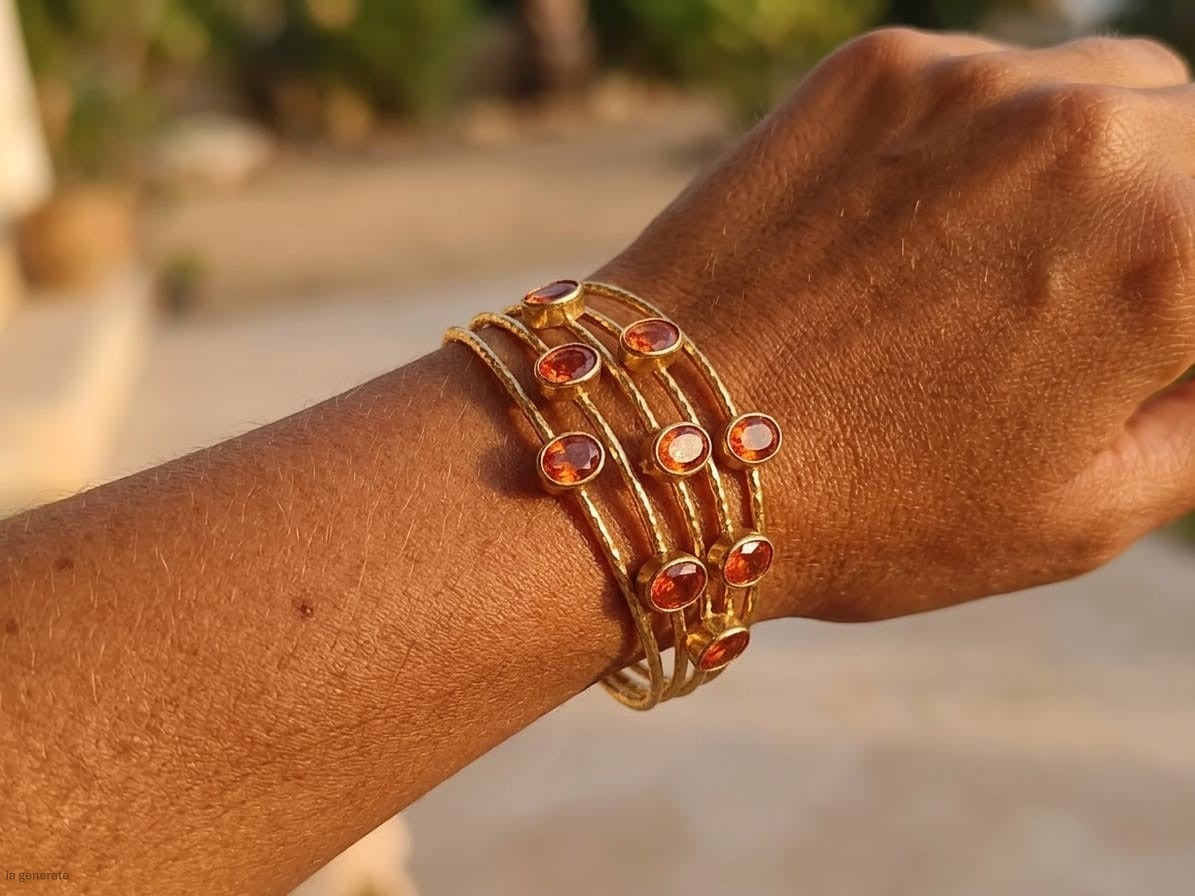 bracciale a cinque fili in bronzo dorato martellato di Rachele Falvo con incastonati nove granati rossi naturali sfaccettati da 3 carat