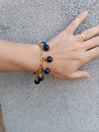 bracciale semirigido in bronzo placcato oro opaco di Rachele Falvo con fusto battuto e sei topazi azzurri naturali pendenti