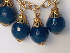 bracciale semirigido in bronzo placcato oro opaco di Rachele Falvo con fusto battuto e sei topazi azzurri naturali pendenti