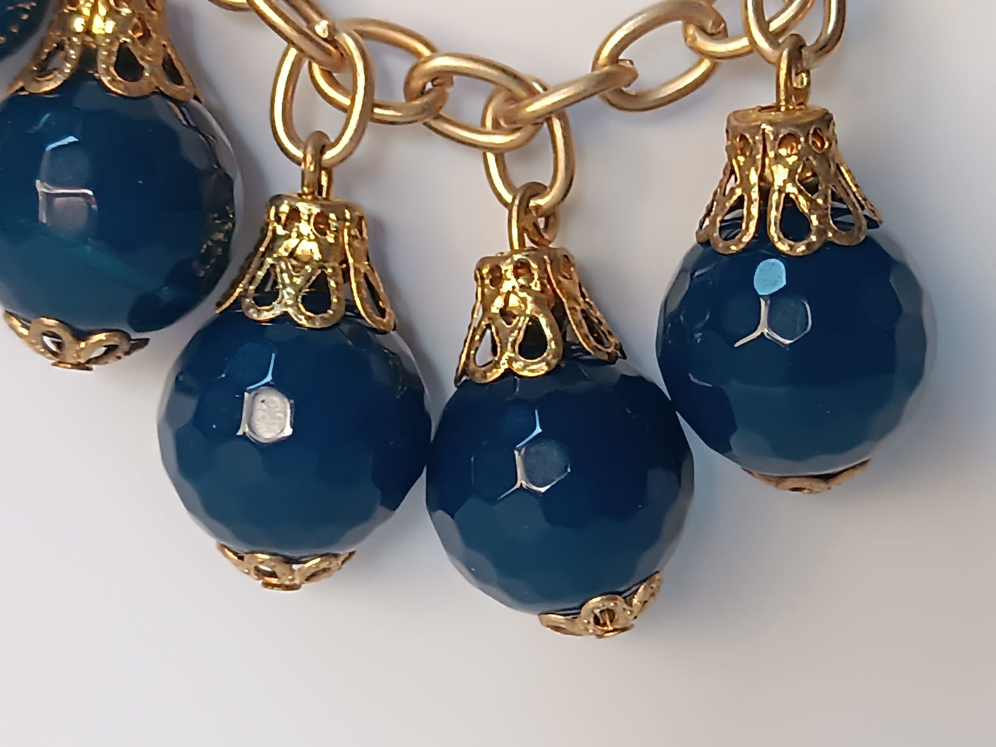 bracciale semirigido in bronzo placcato oro opaco di Rachele Falvo con fusto battuto e sei topazi azzurri naturali pendenti