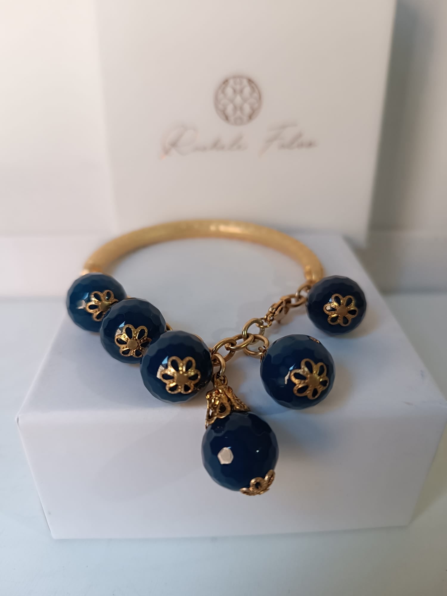 bracciale semirigido in bronzo placcato oro opaco di Rachele Falvo con fusto battuto e sei topazi azzurri naturali pendenti