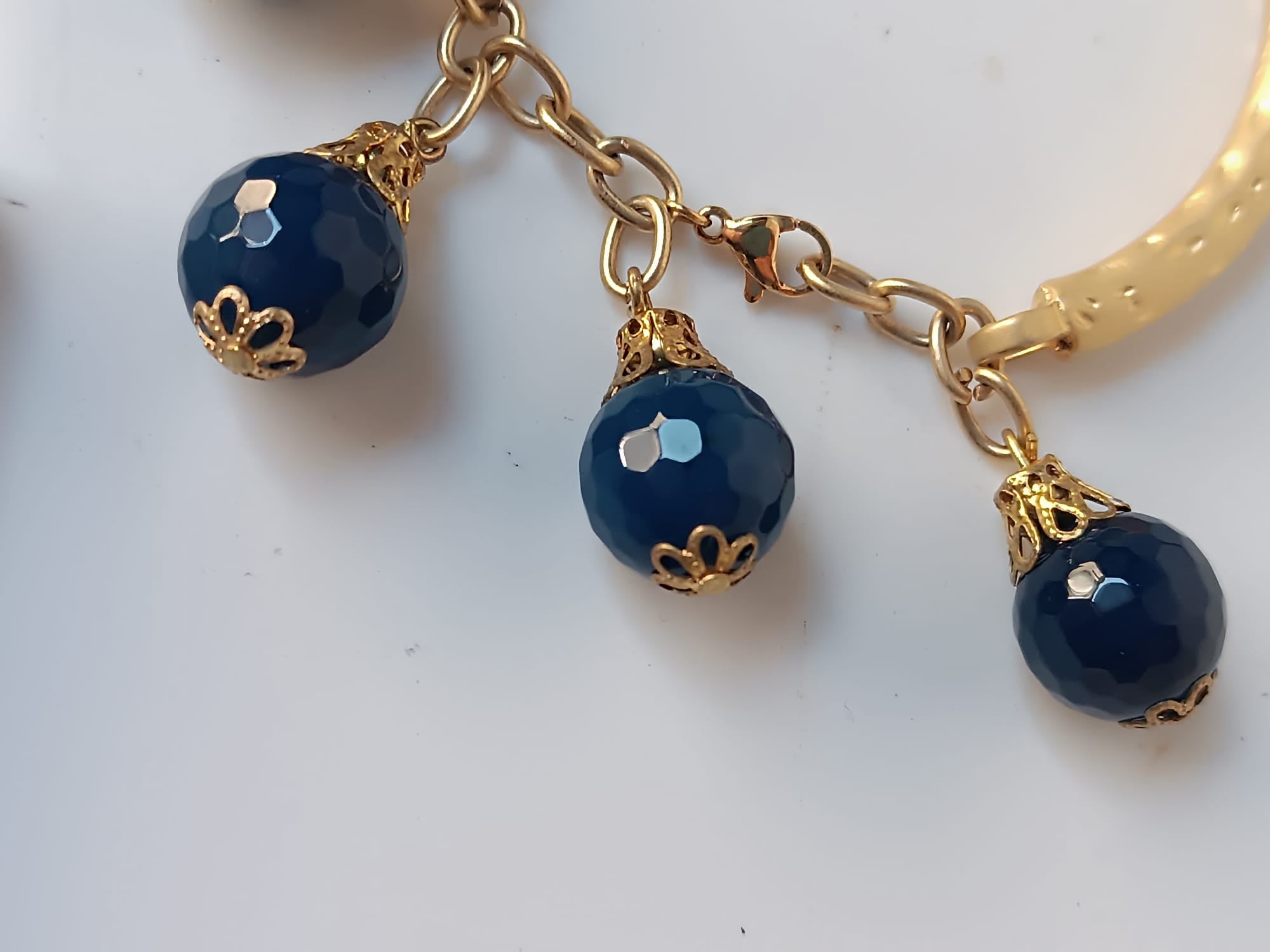 bracciale semirigido in bronzo placcato oro opaco di Rachele Falvo con fusto battuto e sei topazi azzurri naturali pendenti