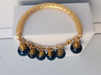 bracciale semirigido in bronzo placcato oro opaco di Rachele Falvo con fusto battuto e sei topazi azzurri naturali pendenti