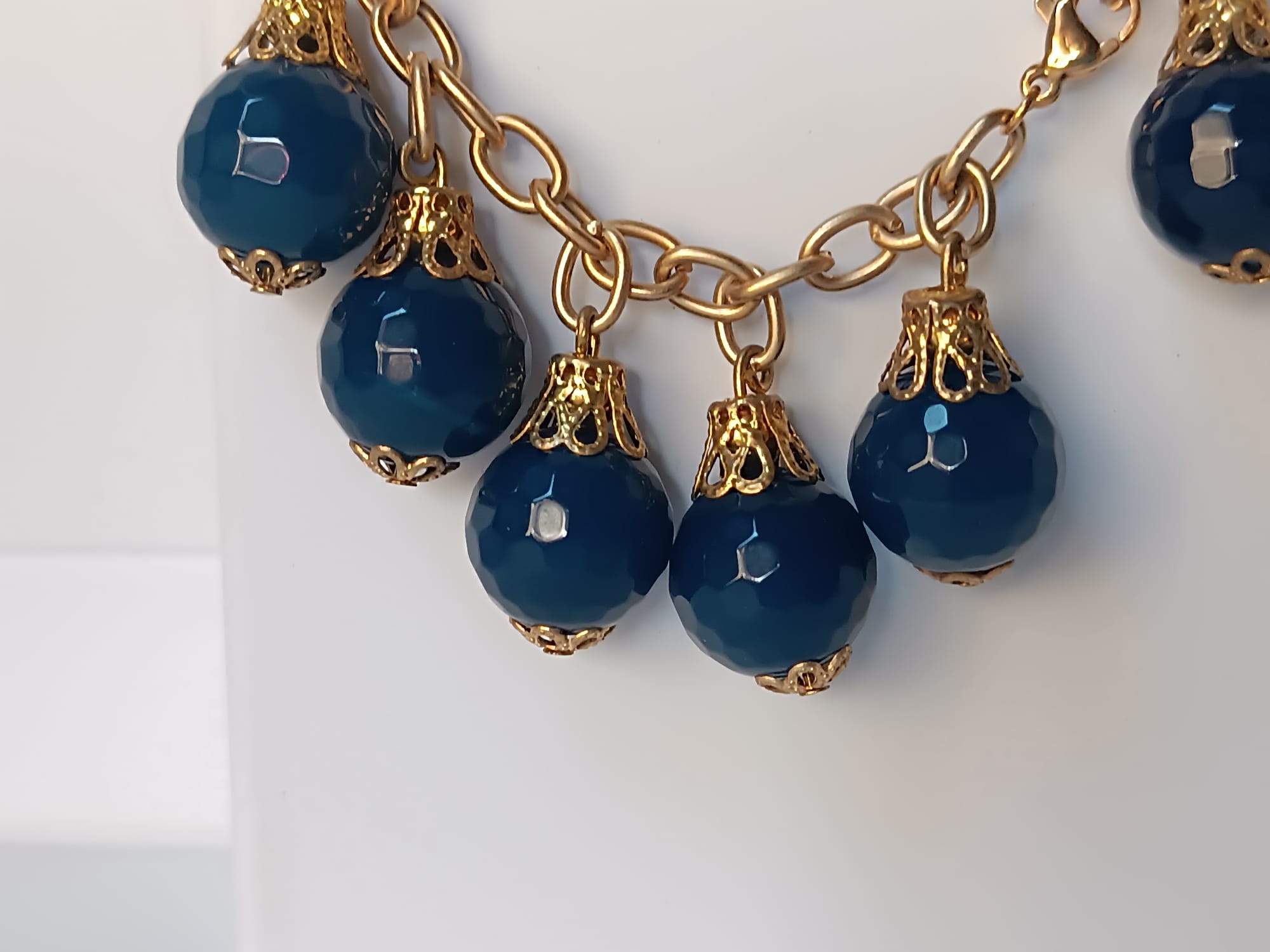 bracciale semirigido in bronzo placcato oro opaco di Rachele Falvo con fusto battuto e sei topazi azzurri naturali pendenti