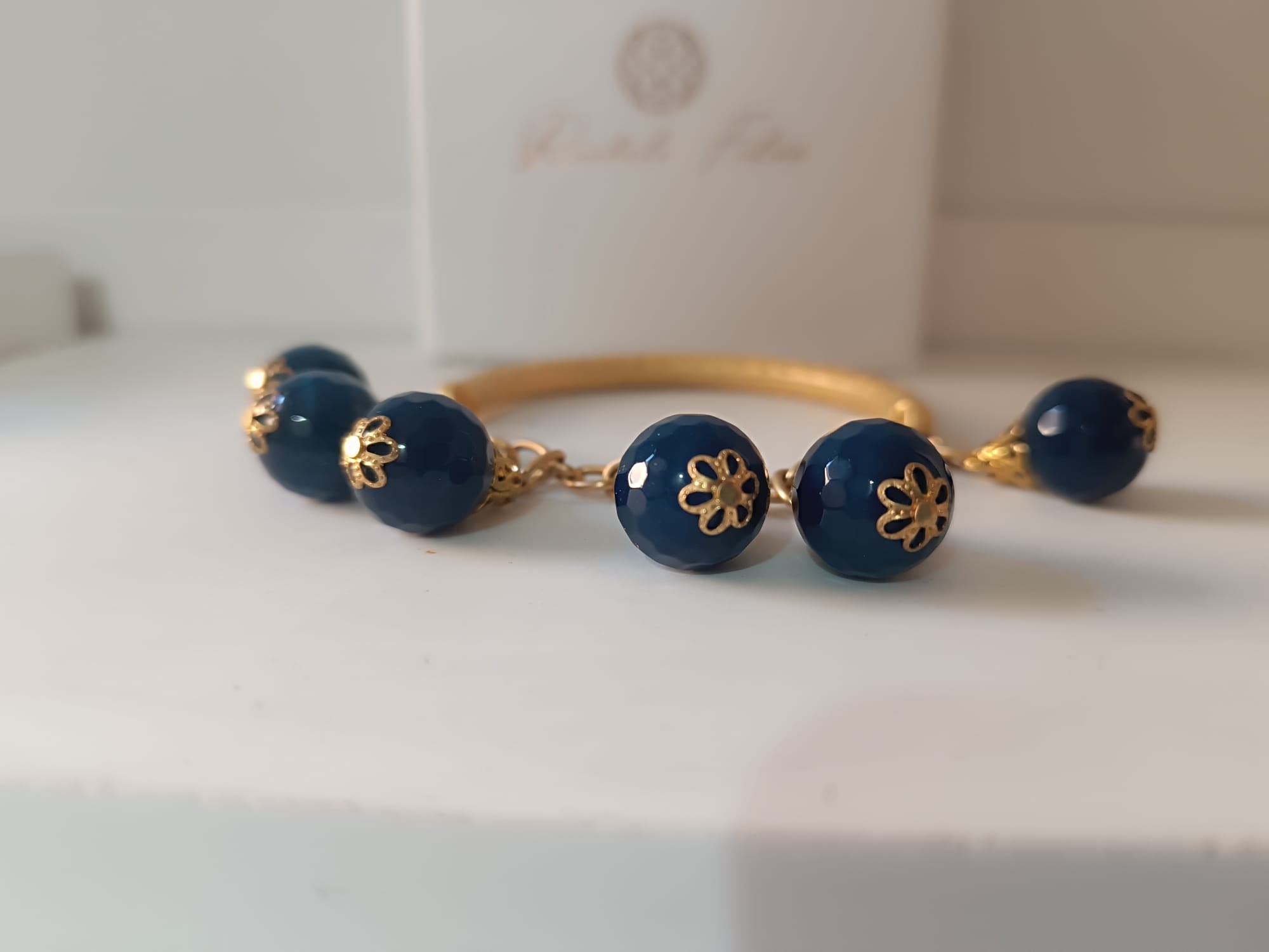 bracciale semirigido in bronzo placcato oro opaco di Rachele Falvo con fusto battuto e sei topazi azzurri naturali pendenti