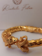  bracciale rigido scultoreo in bronzo dorato di Rachele Falvo con due teste di ariete contrapposte e fusto battuto