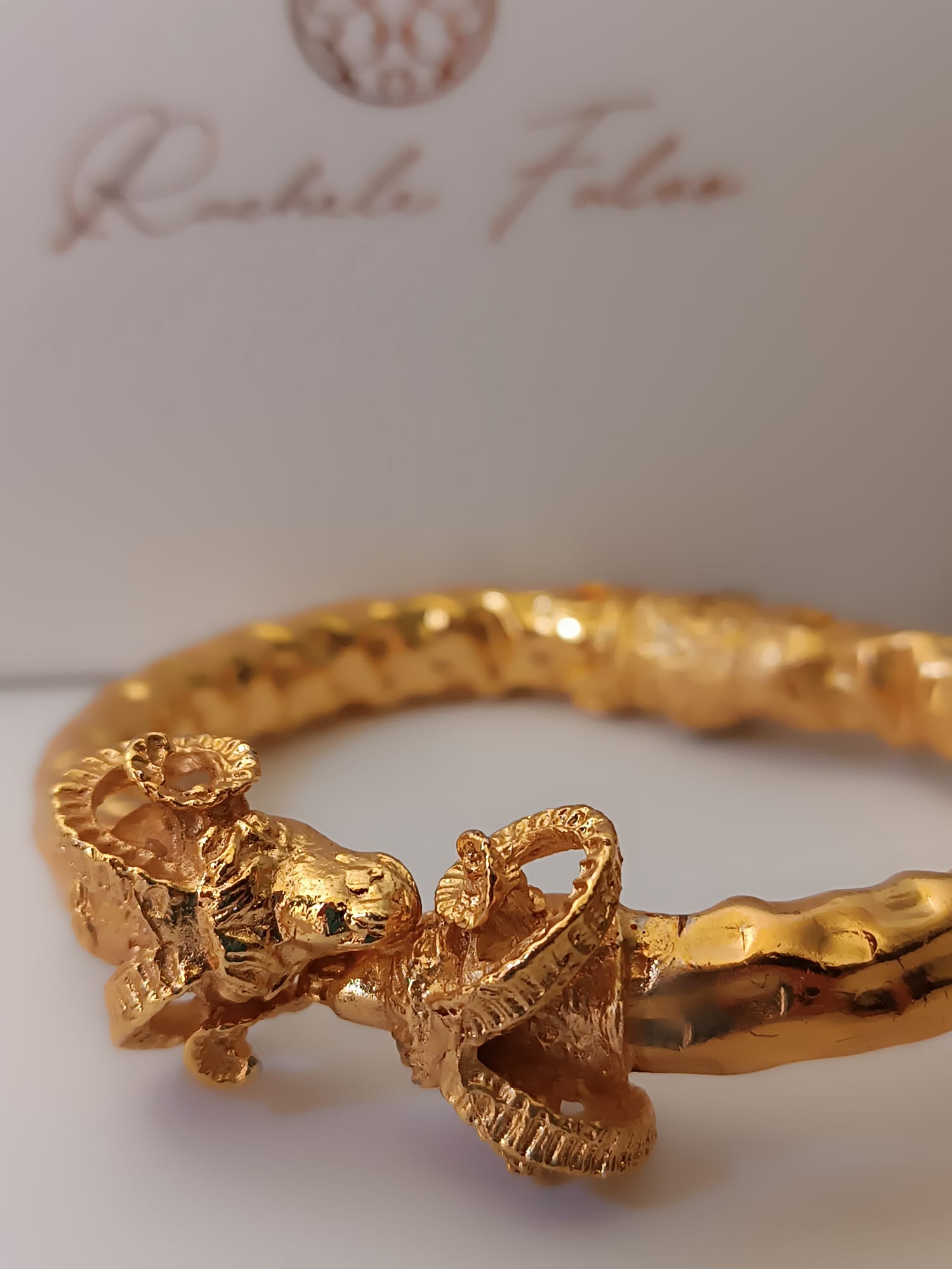  bracciale rigido scultoreo in bronzo dorato di Rachele Falvo con due teste di ariete contrapposte e fusto battuto