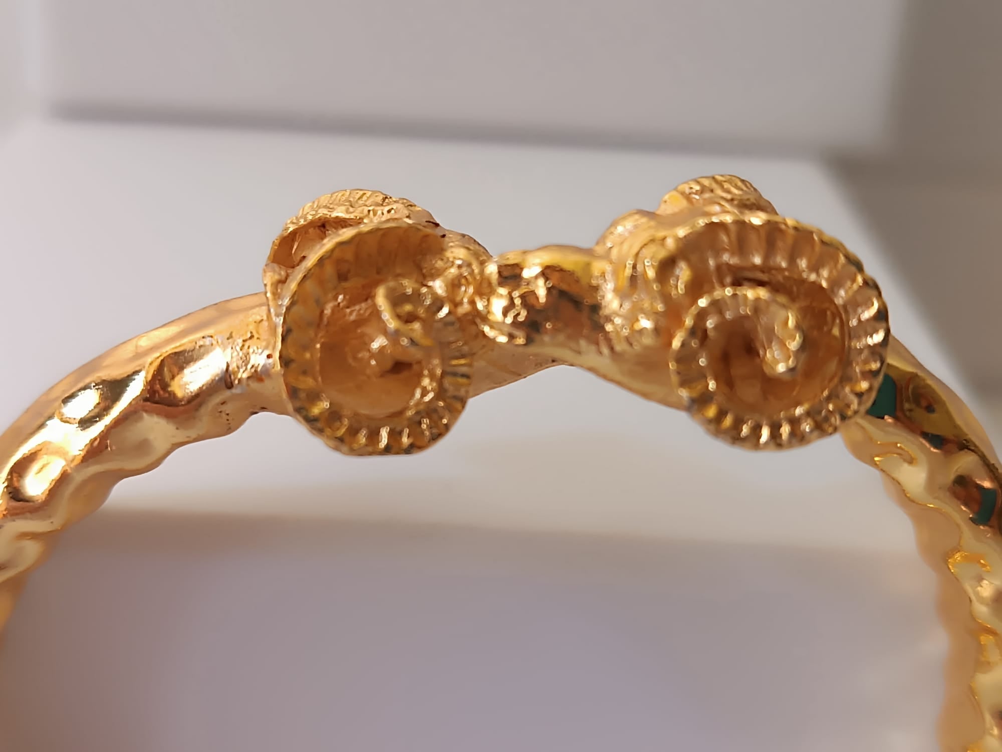  bracciale rigido scultoreo in bronzo dorato di Rachele Falvo con due teste di ariete contrapposte e fusto battuto