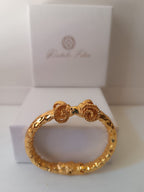  bracciale rigido scultoreo in bronzo dorato di Rachele Falvo con due teste di ariete contrapposte e fusto battuto