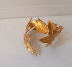 bracciale rigido alto a schiava in bronzo dorato di Rachele Falvo con grandi foglie scultoree sovrapposte
