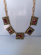 Spettacolare collana girocollo artigianale in bronzo oro opaco con elementi geometrici incastonati di giade verdi e quarzi rosso arancio sfaccettati.