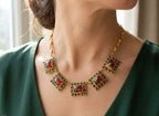 Spettacolare collana girocollo artigianale in bronzo oro opaco con elementi geometrici incastonati di giade verdi e quarzi rosso arancio sfaccettati.