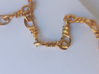 Spettacolare collana girocollo artigianale in bronzo oro opaco con elementi geometrici incastonati di giade verdi e quarzi rosso arancio sfaccettati.