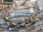 Spettacolare collana girocollo artigianale in bronzo oro opaco con elementi geometrici incastonati di giade verdi e quarzi rosso arancio sfaccettati.