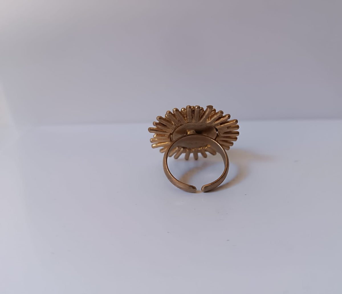 Anello scultoreo a raggiera solare in bronzo dorato con pietra tonda di quarzite azzurra centrale