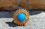 Anello scultoreo a raggiera solare in bronzo dorato con pietra tonda di quarzite azzurra centrale