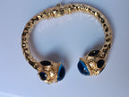 Spettacolare bracciale rigido a molla scultoreo in stile etrusco bizantino in bronzo oro opaco con azzurriti naturali sfaccettate