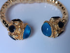 Spettacolare bracciale rigido a molla scultoreo in stile etrusco bizantino in bronzo oro opaco con azzurriti naturali sfaccettate