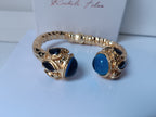 Spettacolare bracciale rigido a molla scultoreo in stile etrusco bizantino in bronzo oro opaco con azzurriti naturali sfaccettate