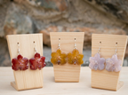 recchini pendenti artigianali con mini orchidee vanda vere in resina lucida e ganci d'argento, mostrate nelle varianti giallo, rosso e bianco