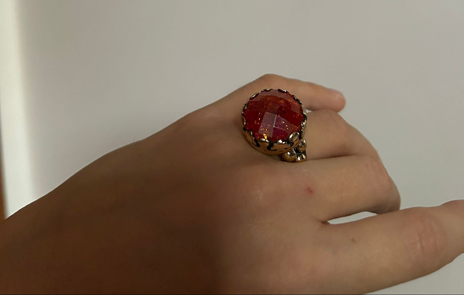 Anello artigianale in argento con avventurina stellata rossa sfaccettata, luminoso e dal design avvolgente.