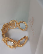  bracciale rigido dorato di Rachele Falvo con texture scultorea e due gemme ovali di madreperla bianca naturale