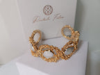  bracciale rigido dorato di Rachele Falvo con texture scultorea e due gemme ovali di madreperla bianca naturale