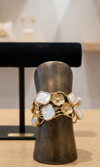 Bracciale rigido multifilo regolabile firmato Rachele Falvo in bronzo dorato, decorato con fiori scultorei in rilievo e grandi placche geometriche di madreperla naturale lucida