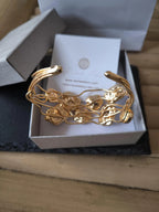 Bracciale rigido multifilo regolabile firmato Rachele Falvo in bronzo dorato, decorato con fiori scultorei in rilievo e grandi placche geometriche di madreperla naturale lucida