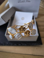 Bracciale rigido multifilo regolabile firmato Rachele Falvo in bronzo dorato, decorato con fiori scultorei in rilievo e grandi placche geometriche di madreperla naturale lucida