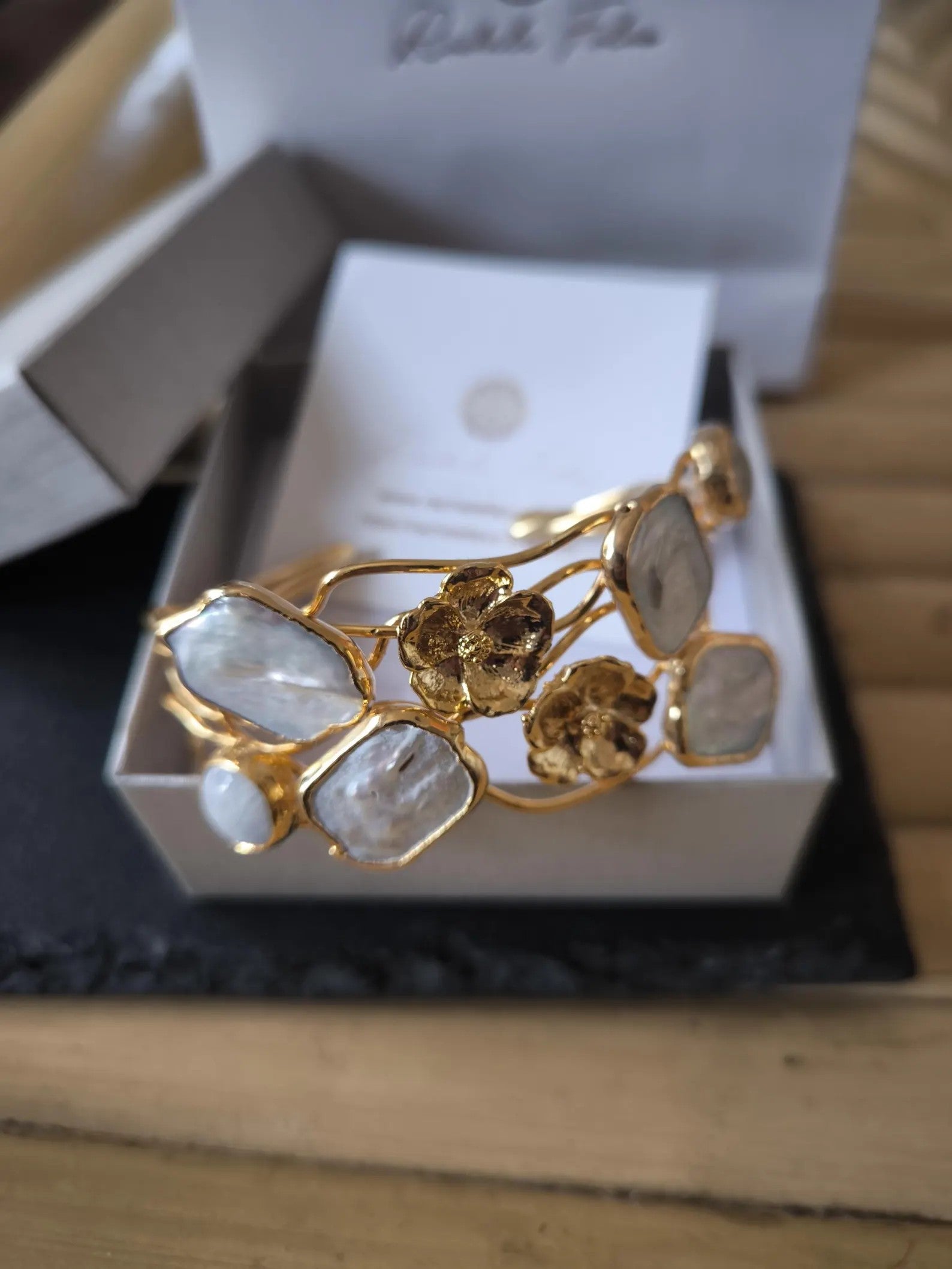 Bracciale rigido multifilo regolabile firmato Rachele Falvo in bronzo dorato, decorato con fiori scultorei in rilievo e grandi placche geometriche di madreperla naturale lucida