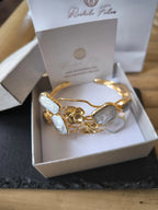 Bracciale rigido multifilo regolabile firmato Rachele Falvo in bronzo dorato, decorato con fiori scultorei in rilievo e grandi placche geometriche di madreperla naturale lucida