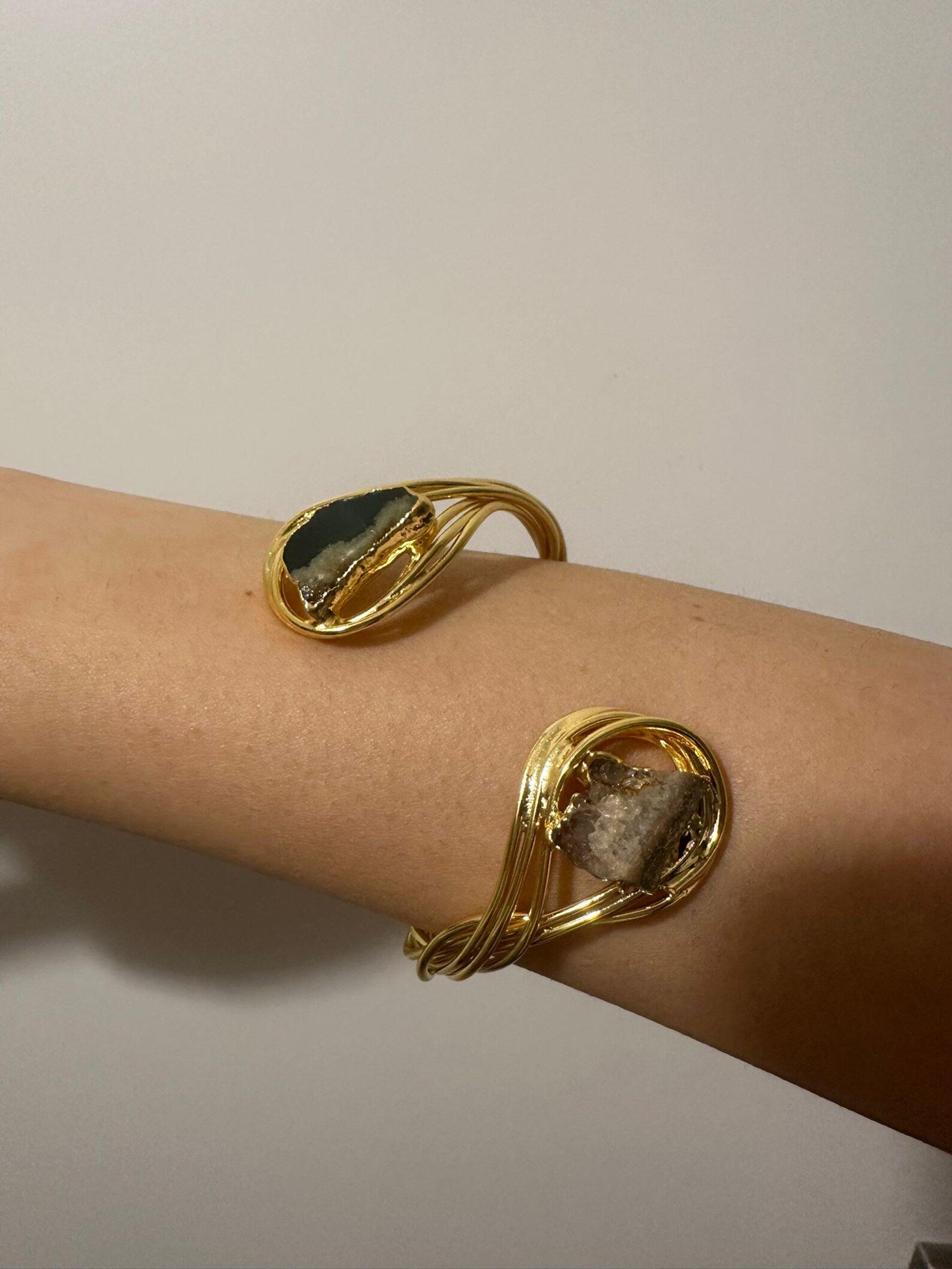 Bracciale scultoreo rigido a spira contrarié firmato Rachele Falvo, realizzato in fili di bronzo dorato intrecciati a mano con incastonate un'agata striata naturale e un'ametista in druza grezza,