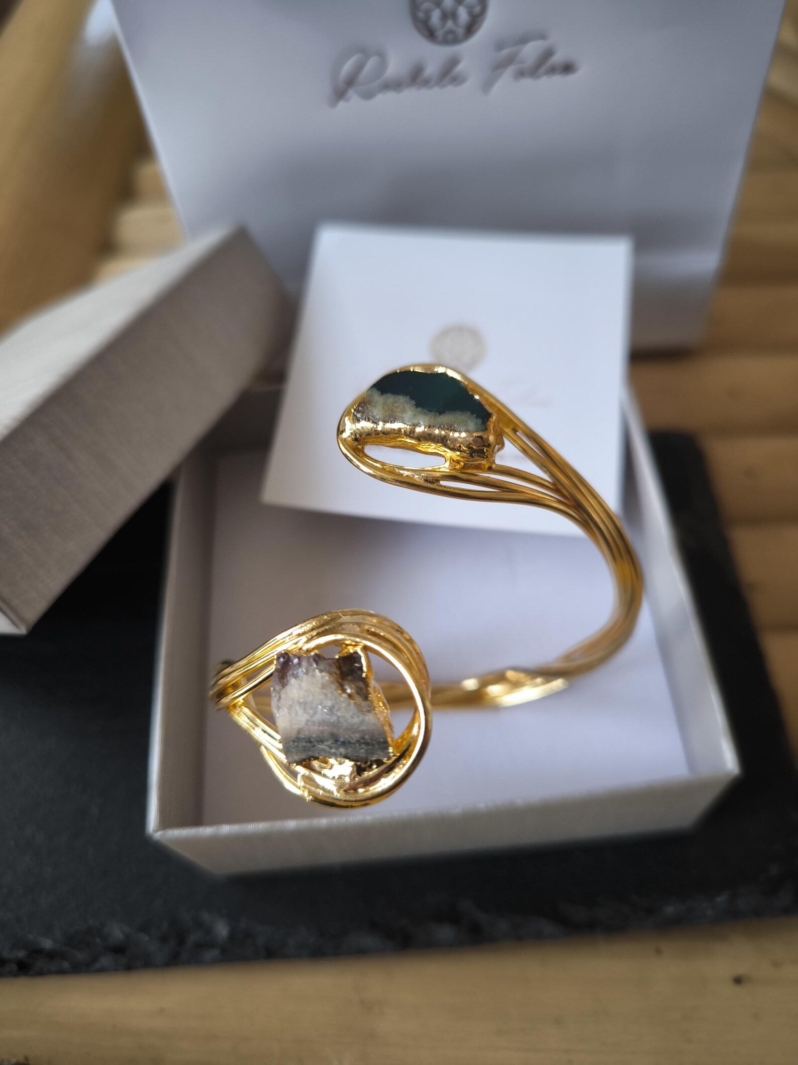 Bracciale scultoreo rigido a spira contrarié firmato Rachele Falvo, realizzato in fili di bronzo dorato intrecciati a mano con incastonate un'agata striata naturale e un'ametista in druza grezza,